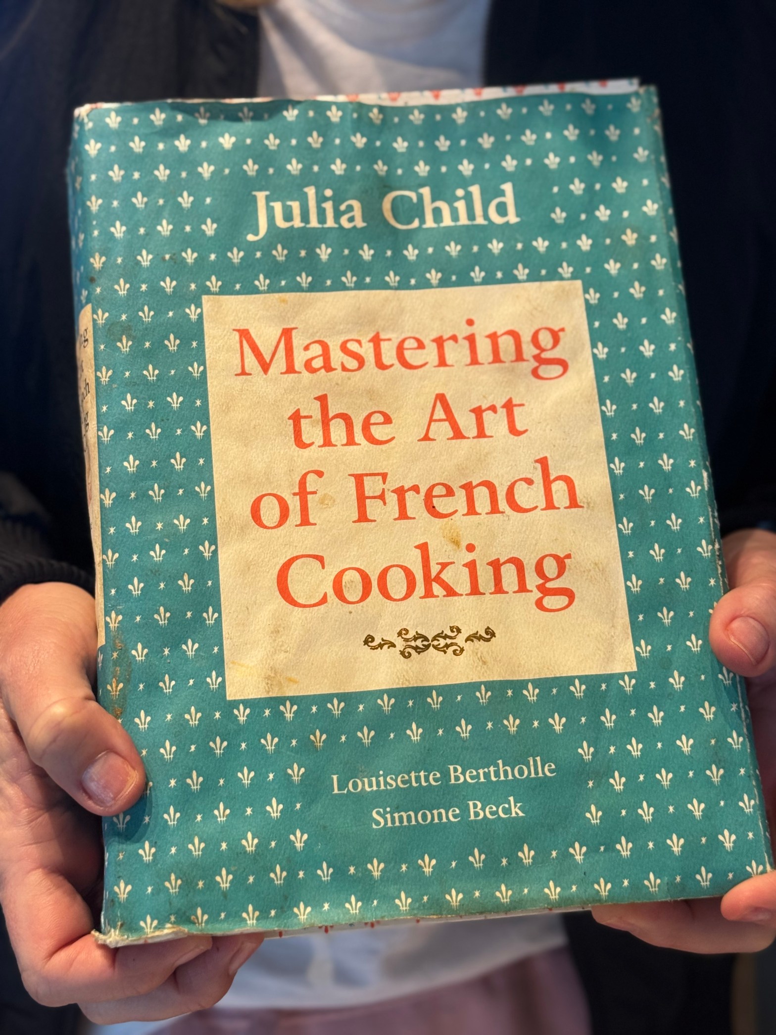 Mastering the Art of French Cooking, cookbook in a woman's hands.