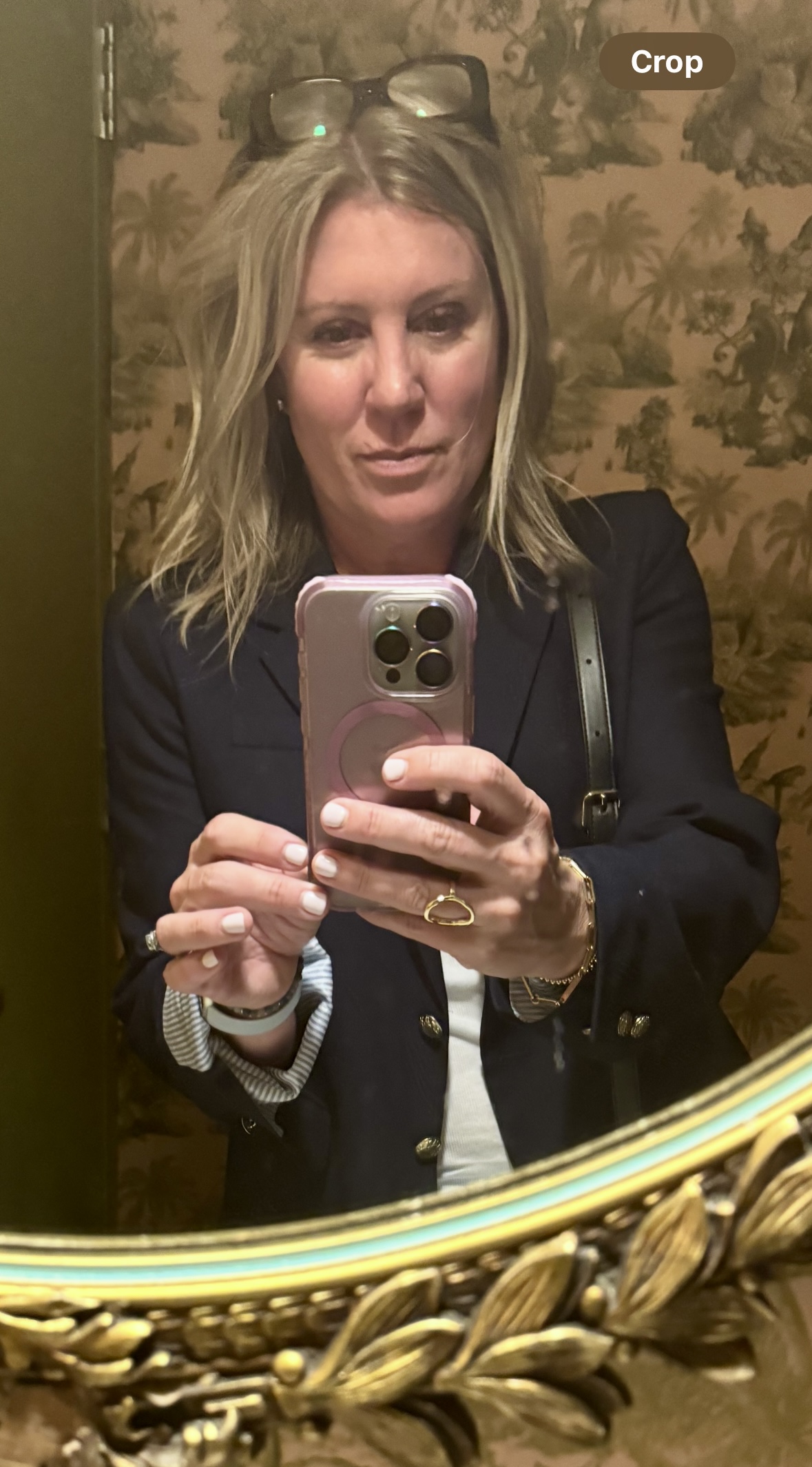 blond woman taking a selfie in a bathroom mirror.