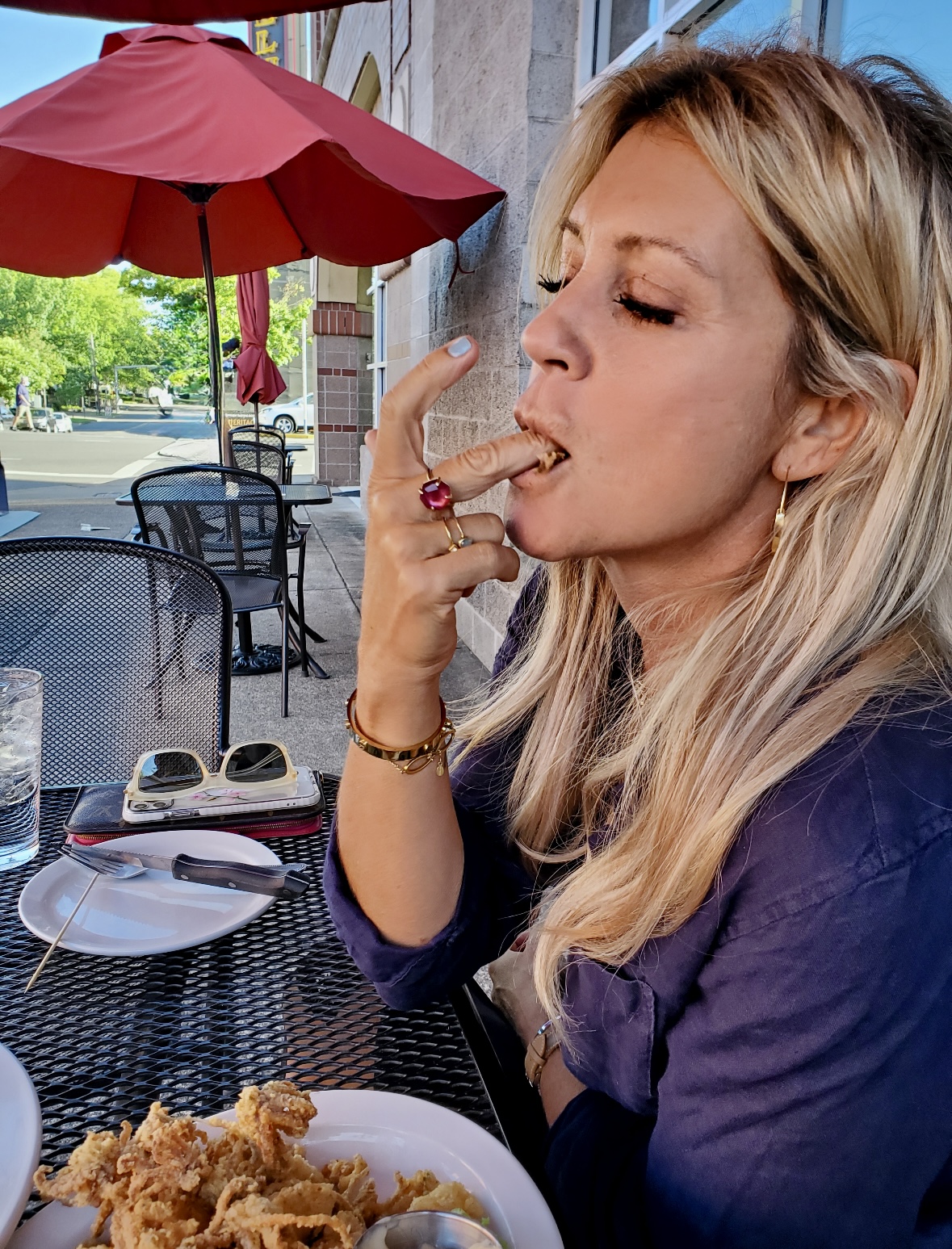 Blond woman licking her fingers enjoying fried food.