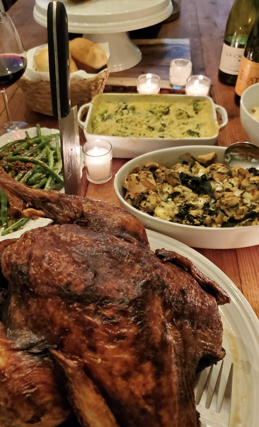 Table with a roasted turkey and other Thanksgiving dishes.
