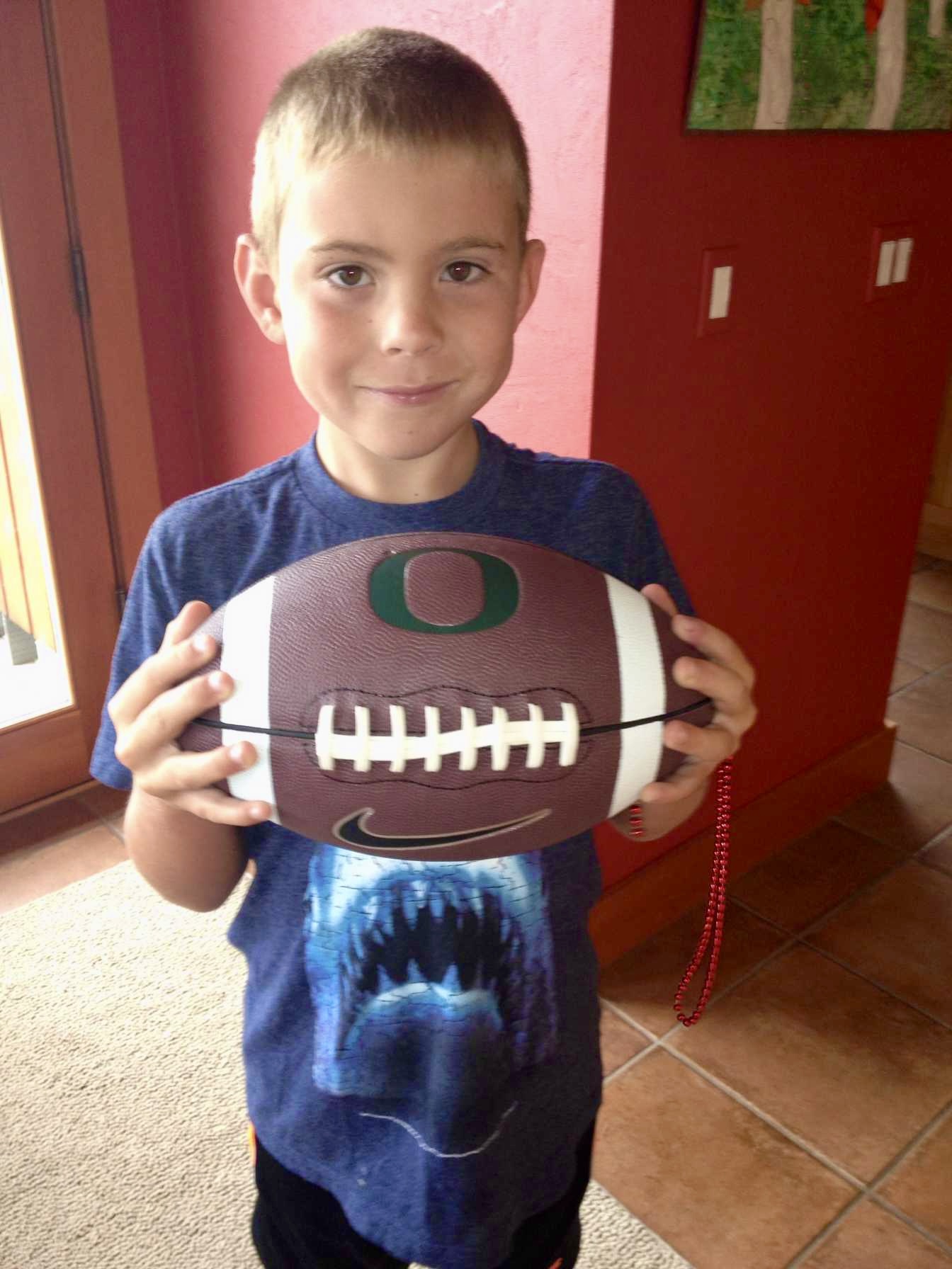 Young boy smiling holding a football.