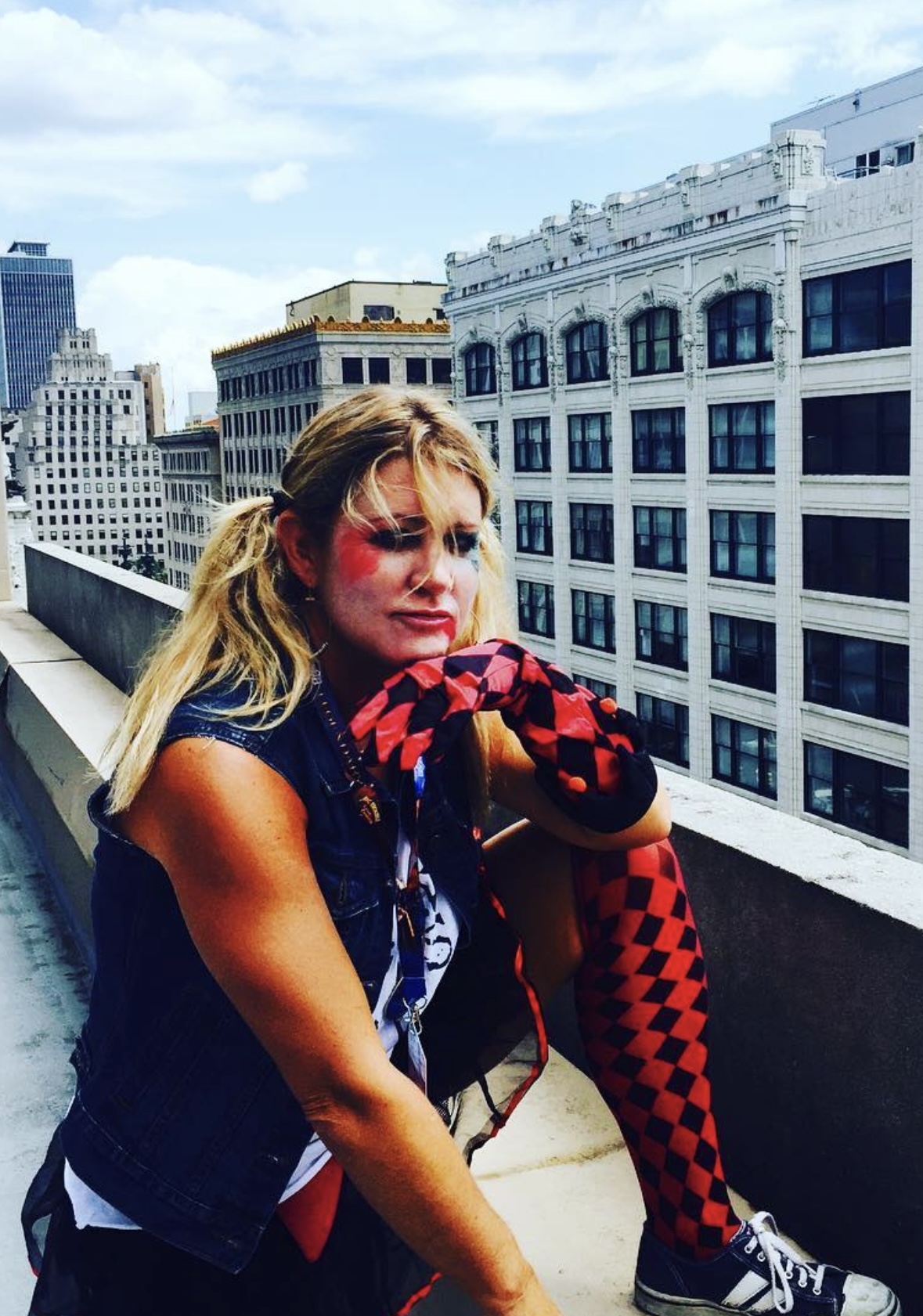 Blond woman dressed up as Harley Quinn on the top of a building.